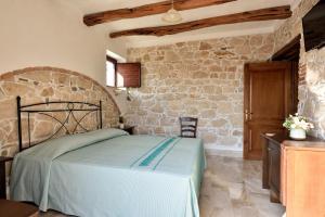 a bedroom with a bed and a stone wall at Hotel Goloritzé in Baunei