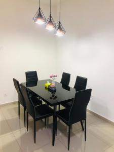 une salle à manger avec une table noire et des chaises noires dans l'établissement De Little Cabin - 7mins to Sunway Iost World of Tambun, à Ipoh
