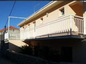 a building with a balcony with a white railing at Mikulin Apartments in Lumbarda