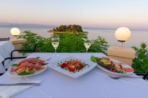 una mesa con dos platos de comida y copas de vino en Aegli Hotel en Perama