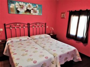 Casa Rural La Dehesa في La Mata: غرفة نوم بجدران حمراء وسرير ببطانية