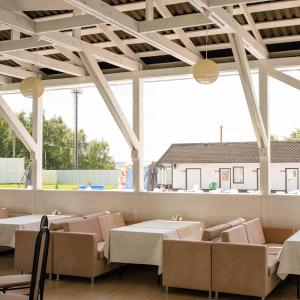 a restaurant with tables and chairs and large windows at Lyudmila in Podgorenskiy