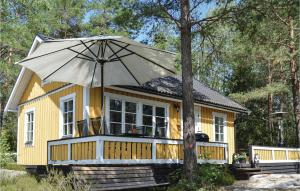 una pequeña casa amarilla con una sombrilla grande en Lovely Home In Strngns With Kitchen en Strängnäs
