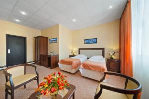 ヴォロネジにあるVoronezh Hotelのベッド2台、テーブルと椅子が備わるホテルルームです。