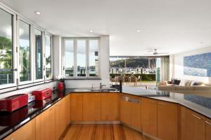 a kitchen with wooden cabinets and a large window at Pavillion 17 - Waterfront Spacious 4 Bedroom With Own Inground Pool And Golf Buggy in Hamilton Island