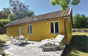 フンボストランドにあるAmazing Home In Hunnebostrand With 1 Bedroomsの小さな黄色の家(椅子、テーブル付)