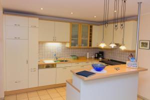 una cocina con armarios blancos y un tazón azul en una encimera en Gästehaus Heitkamp, en Lüdinghausen