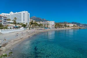 eine Gruppe von Menschen an einem Strand in der Nähe des Wassers in der Unterkunft Apartamentos Mombasa 2 planta in Nerja