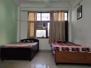 two beds in a room with a window at Paradise Villa in Vrindāvan
