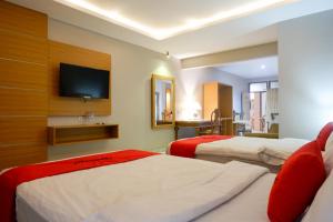 a hotel room with two beds and a flat screen tv at RedDoorz Plus at Hotel Srikandi Kendari in Kendari