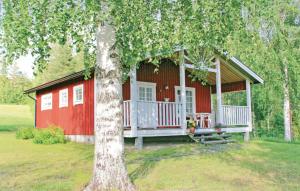 a red cabin with a porch and a tree at Beautiful Home In Vindeln With 2 Bedrooms And Wifi in Bergnäs