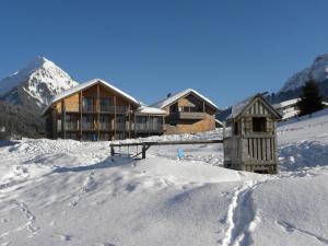 a ski lodge in the snow with mountains in the background at n Apartments Hotel in Schoppernau
