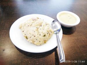 un plato de comida con una cuchara y un tazón de salsa en Hotel Sai Residency, en Vasai