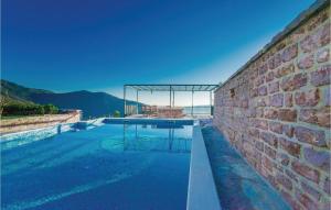 a swimming pool in a brick wall with a table at 3 Bedroom Beautiful Home In Tivat in Tivat
