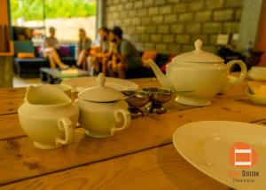 a wooden table with two tea pots and plates on it at Bunk Station in Ella