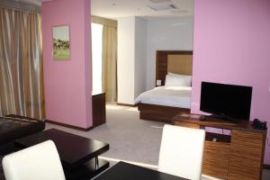 a room with a bed and a living room with a tv at Hotel Franca in Pljevlja