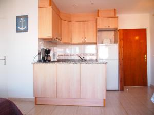 a kitchen with wooden cabinets and a white refrigerator at Miramar 32C in Roses