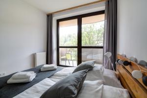 a bedroom with a bed and a large window at Krynica Apartamenty Rodzinny Apartament w Centrum 43 in Krynica Zdrój