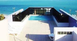 una piscina con el océano al fondo en Beira Mar Apartmento 306, en Maceió