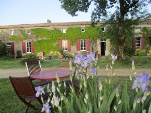 einen Tisch und Stühle vor einem Haus mit lila Blumen in der Unterkunft Logis de Bois Roche (2) in Saint-Bonnet-sur-Gironde