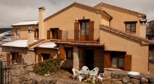 une maison avec une table et des chaises devant elle dans l'établissement Casa de la Yaya, à Hoyos del Espino