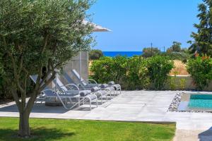 - une rangée de chaises longues à côté de la piscine dans l'établissement Olive Tree House, à Gennadi