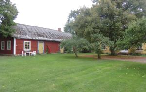 a red house with a grass yard next to a building at Stunning Home In Borgholm With Kitchen in Borgholm