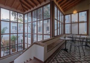 Großes Zimmer mit Fenstern, einer Treppe und einem Tisch in der Unterkunft Agora Residence in Chios