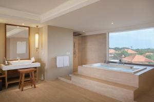 a bathroom with a tub and a sink and a mirror at Royal Suites at The Bandha in Legian