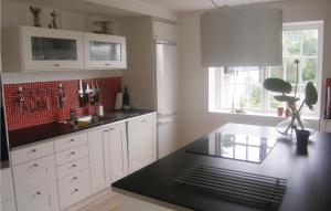 a kitchen with white cabinets and a black counter top at Nice Home In Beddingestrand With Sauna in Beddinge Strand +9 photos