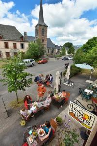 a group of people sitting at tables in front of a church at Auberge De La Providence in Saint-Donat