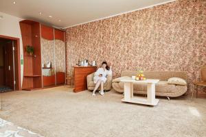 a woman sitting on a couch in a living room at Hotel Anzas in Abakan