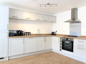 una cocina blanca con armarios y electrodomésticos blancos en The Martins, en Peterborough