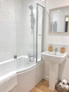Baño blanco con lavabo, bañera y espejo en The Martins, en Peterborough