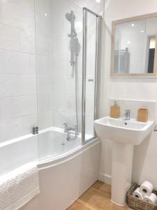 a white bathroom with a sink and a tub and a mirror at The Martins in Peterborough