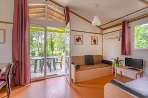 a living room with a couch and a television and a table at Lagrange Grand Bleu Vacances – Résidence Port Lalande in Castelmoron-sur-Lot