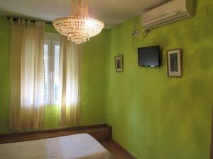 a bedroom with green walls and a chandelier and a window at Hostal Pradillo in Móstoles