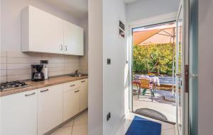 eine Küche mit weißen Schränken und eine Tür zu einer Terrasse in der Unterkunft 1 Bedroom Stunning Apartment In Opatija in Opatija
