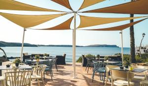 a patio with tables and chairs and an umbrella at Comitas Tramontana Park in Fornells