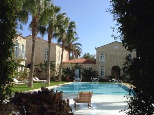 a swimming pool in front of a house with palm trees at Manastir Alacati Hotel in Alaçatı