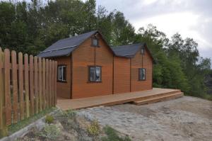 a small wooden house with a wooden deck at Wiatrak in Ręboszewo