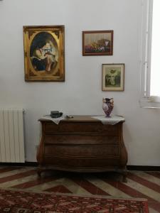 a wooden dresser in a room with paintings on the wall at B&B Palazzo Antonelli in Monopoli