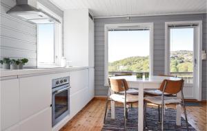 uma cozinha com mesa, cadeiras e janelas em Nice Home In Lindesnes With Kitchen em Stutsvig