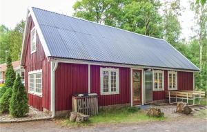 una casa roja con techo solar y banco en Amazing Home In Eringsboda With Wifi, en Pålsmåla