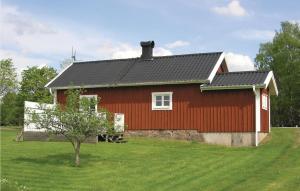 a red barn with a tree in front of it at Lovely Home In Ambjrnarp With Lake View in Ambjörnarp