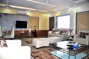 a living room with white furniture and a flat screen tv at The Bhopal Grande in Bhopal