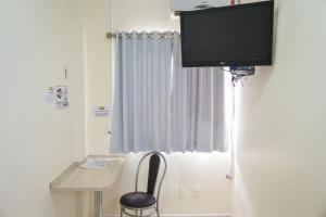 ein Zimmer mit einem Schreibtisch und einem Fernseher an der Wand in der Unterkunft Hotel Scoz in Pouso Redondo