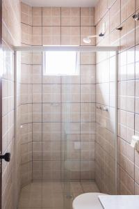 uma casa de banho com uma cabina de duche em vidro e um WC. em Hotel Scoz em Pouso Redondo