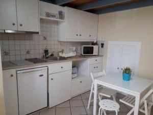 エルムポリにあるErmoupolis, Syros City Apartmentsの白いキャビネット、白いテーブルと椅子付きのキッチン