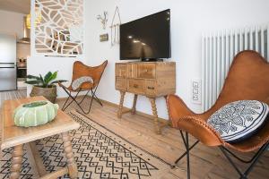 een woonkamer met stoelen en een flatscreen-tv bij #FLH - Boho Chic Apartment, Agia Sofia District in Thessaloniki